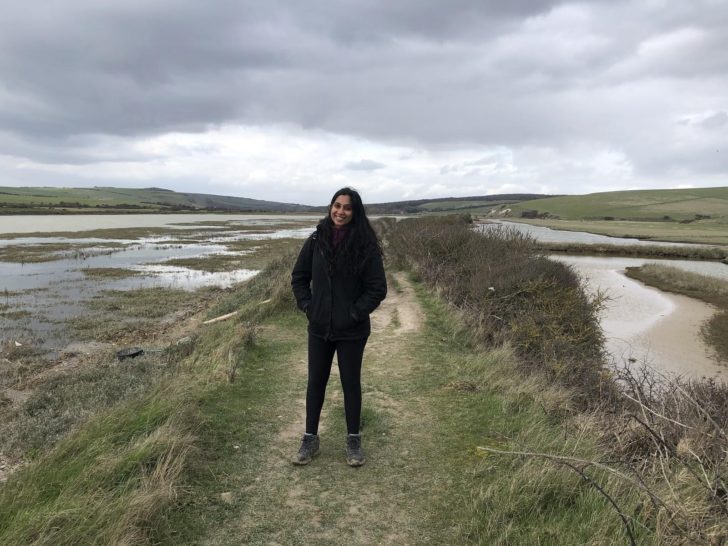 Woman standing on sea path with grey clouds overhead