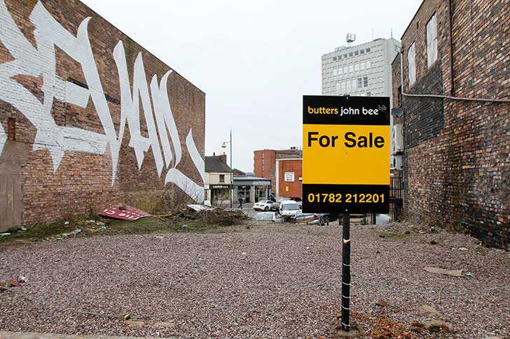 A patch of disused land with a For Sale sign