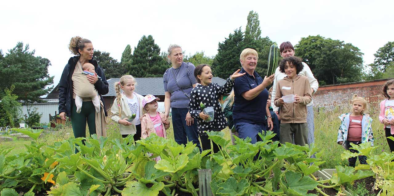 Women and children stand in a garden and admire vegetables growing