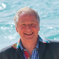 A smiling man in front of the sea