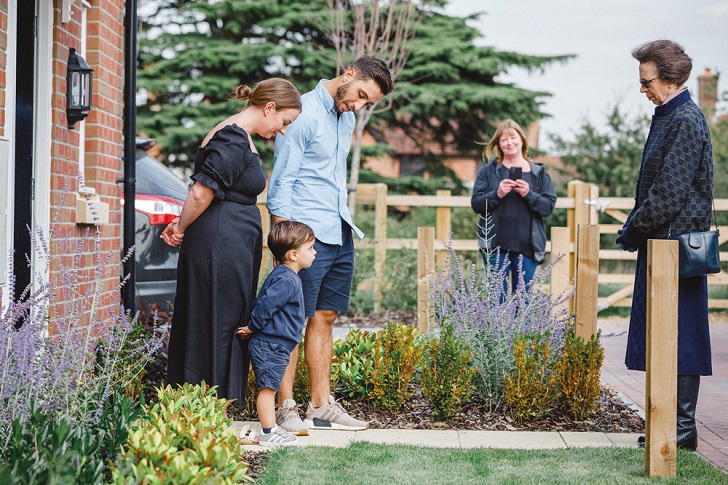 A couple and child greeting the Princess Royal outside their new home