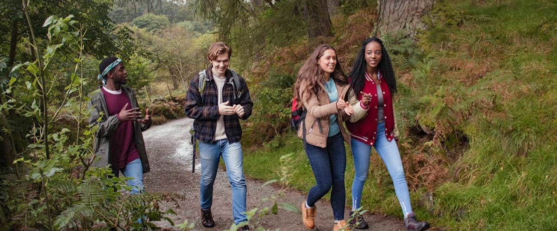 Two young women and two young men on a walk on a rural path