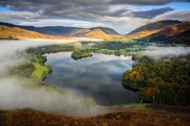 A lake surrounded by hills and a thin layer of mist