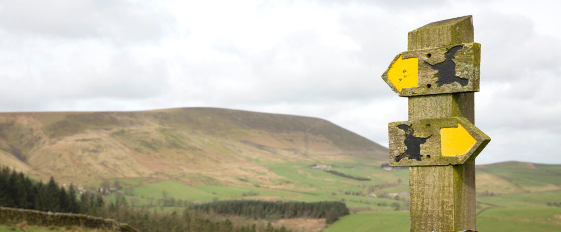 Footpath signs with Pendle Hill in the background above the village of Barley, in the Borough of Pendle Lancashire