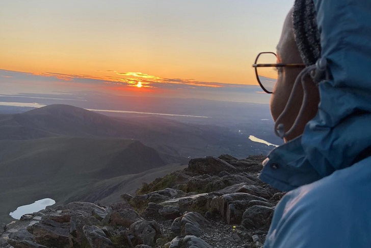 A woman looking over mountains and tarns at sunset