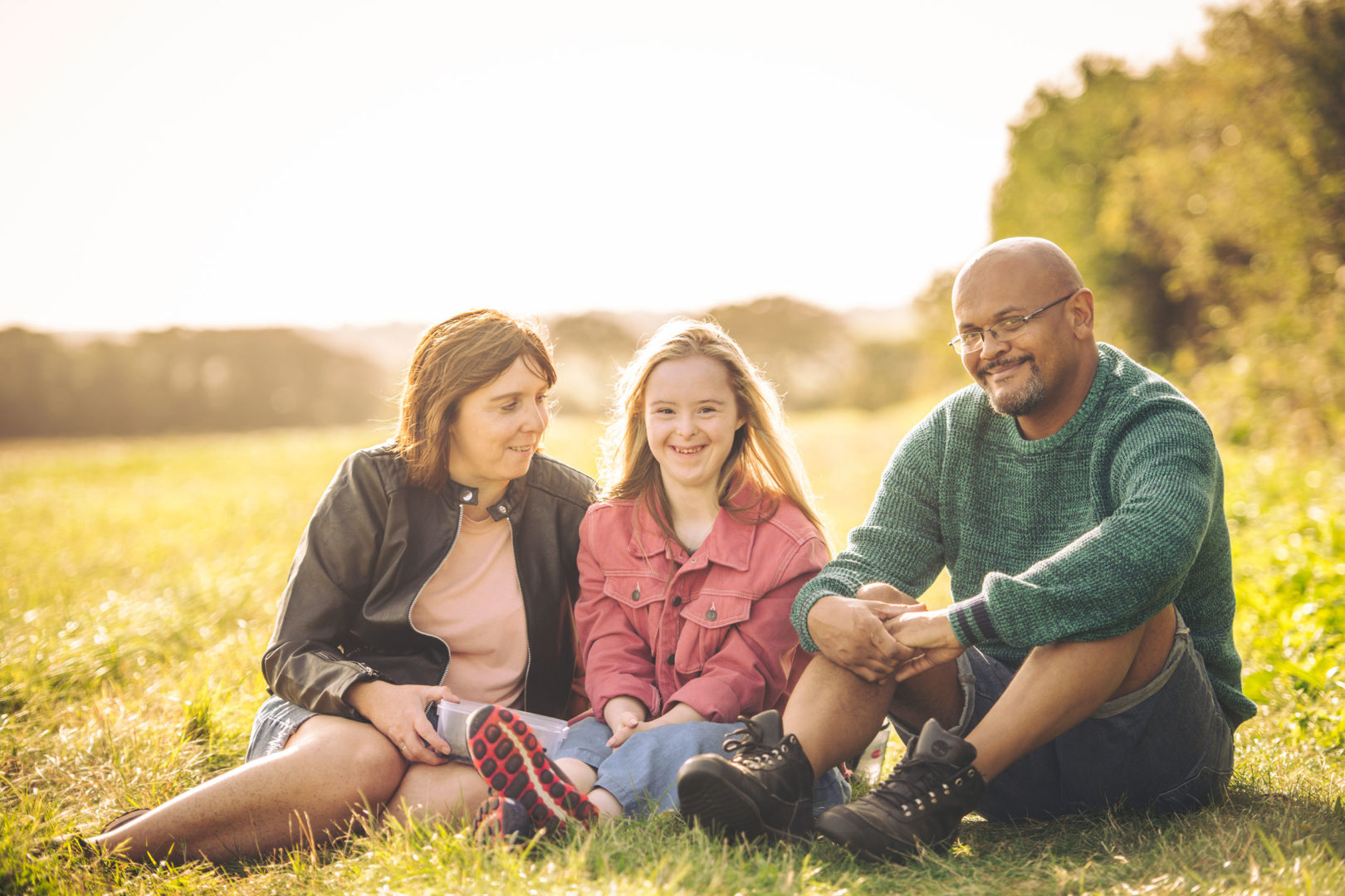 A family sat in a field on a sunny day