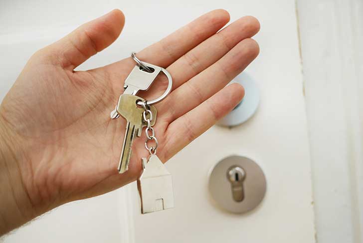 A hand holding keys with a house-shaped keyring