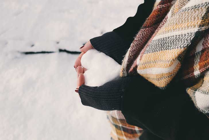 Hands holding a heart-shaped snowball