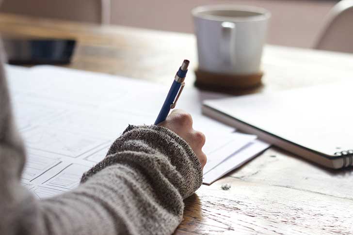 A person holding a pen writing on paper