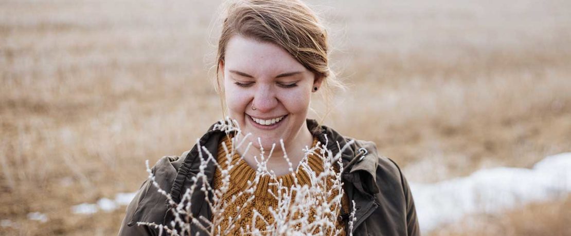 A woman smiles and looks down in a frosty field