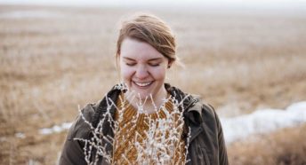 A woman smiles and looks down in a frosty field