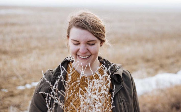 A woman smiles and looks down in a frosty field