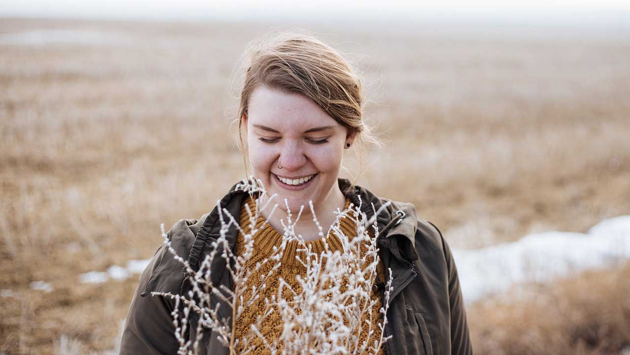 A woman smiles and looks down in a frosty field