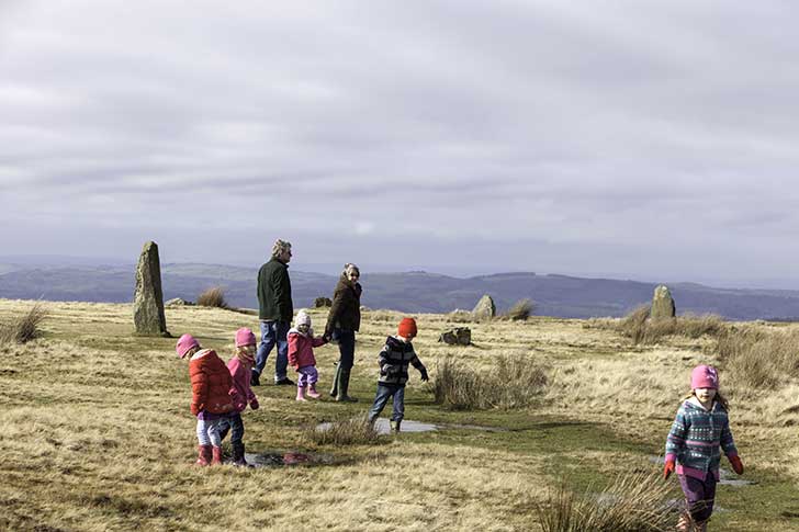 Two adults and four small children walk between imposing pointed stones