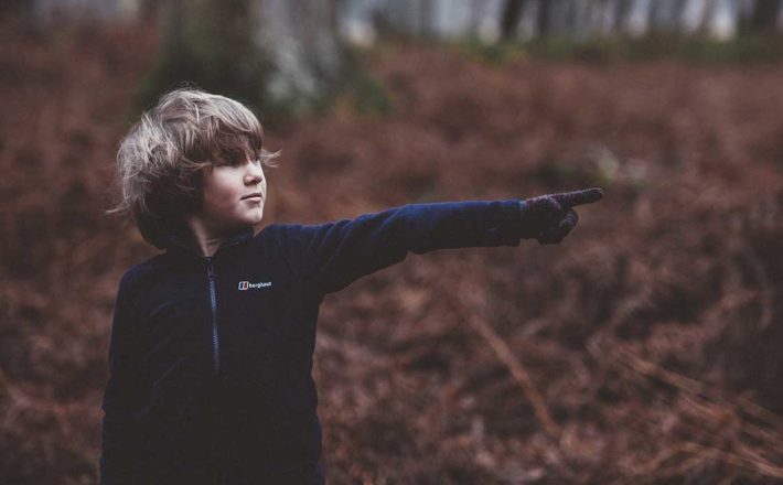 Young boy pointing in chilly forest