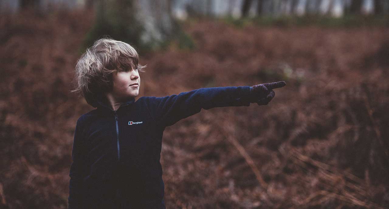 Young boy pointing in chilly forest