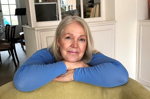 A smiling woman in blue leaning on a table