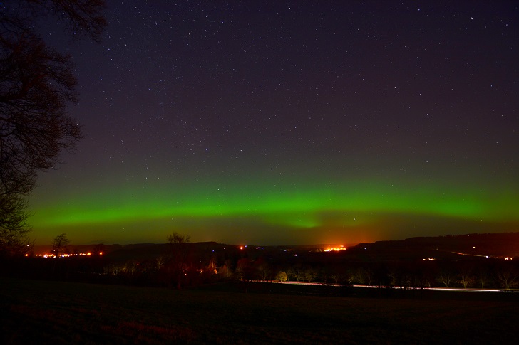 Green glow of the Northern Lights in a dark night sky