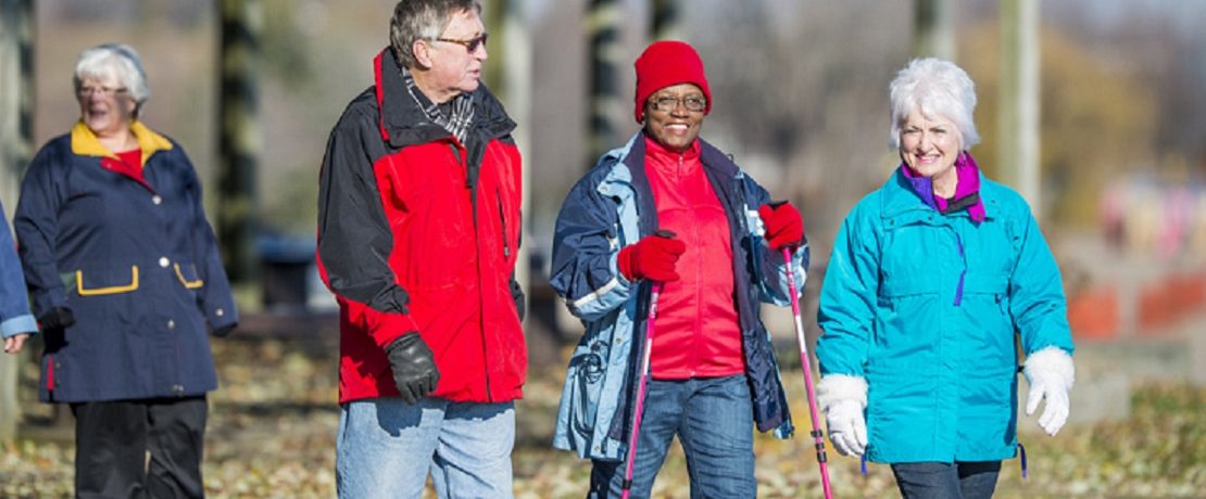 A group of older adults walking with sticks in coats