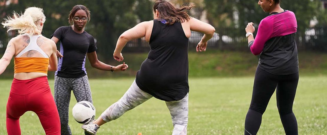 A group of women kicking a football around on grass