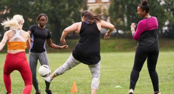A group of women kicking a football around on grass