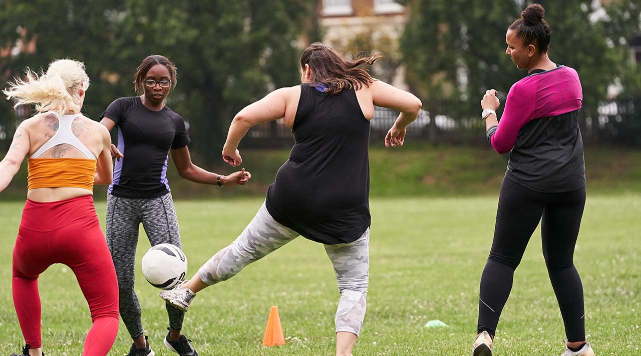 A group of women kicking a football around on grass