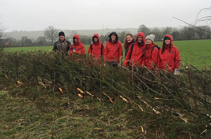 A group of young conservationists in red anoraks in misty landscape