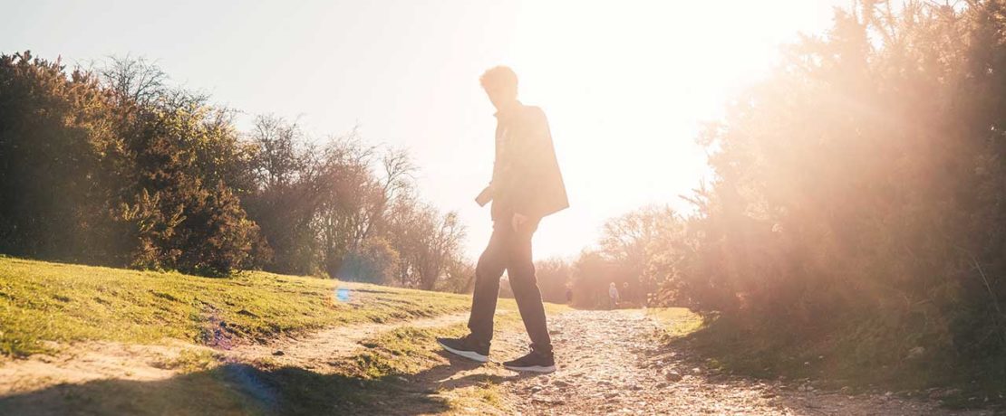 A bright ray of sunlight behind a person walking outdoors