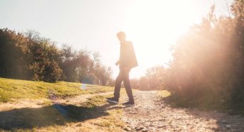 A bright ray of sunlight behind a person walking outdoors