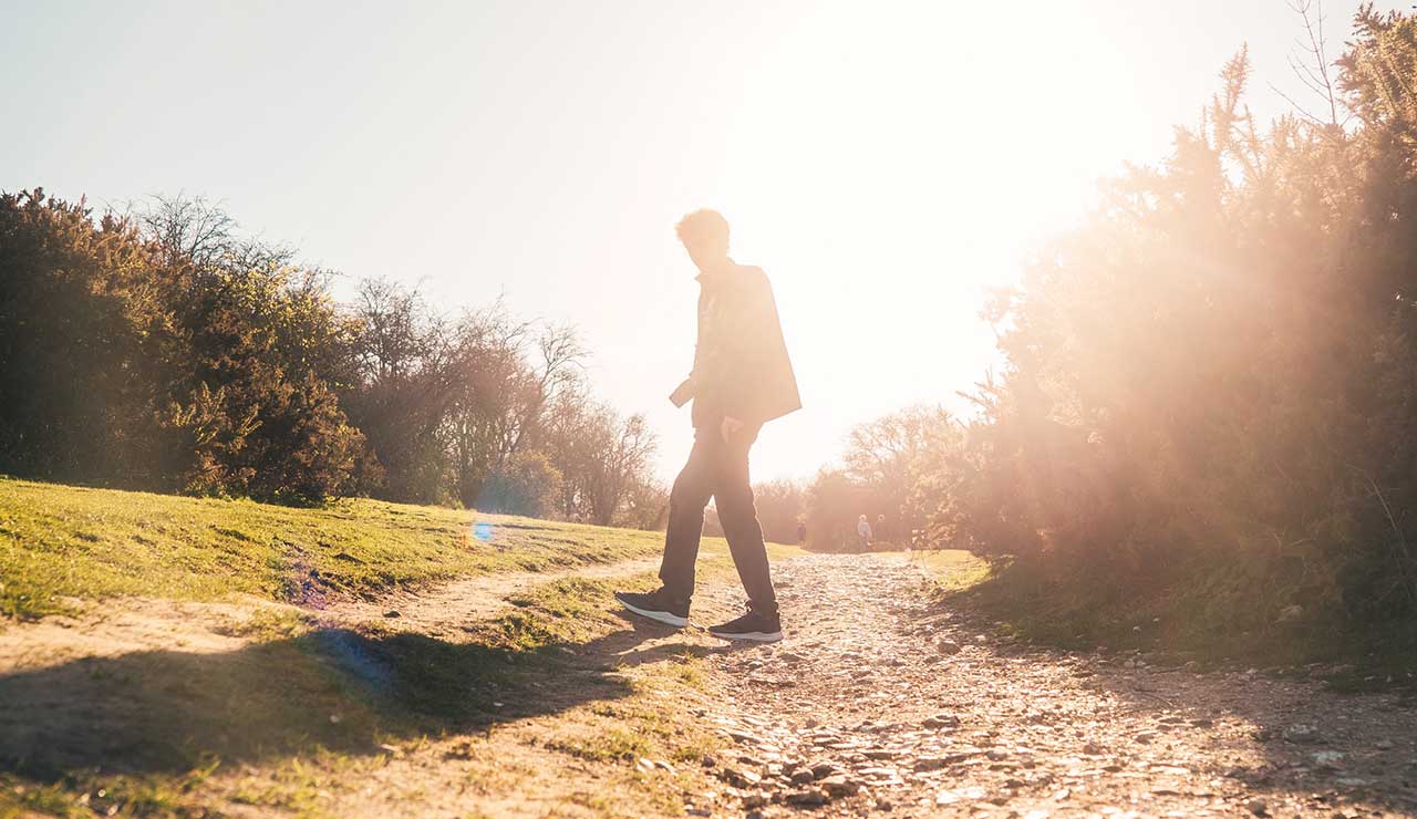 A bright ray of sunlight behind a person walking outdoors