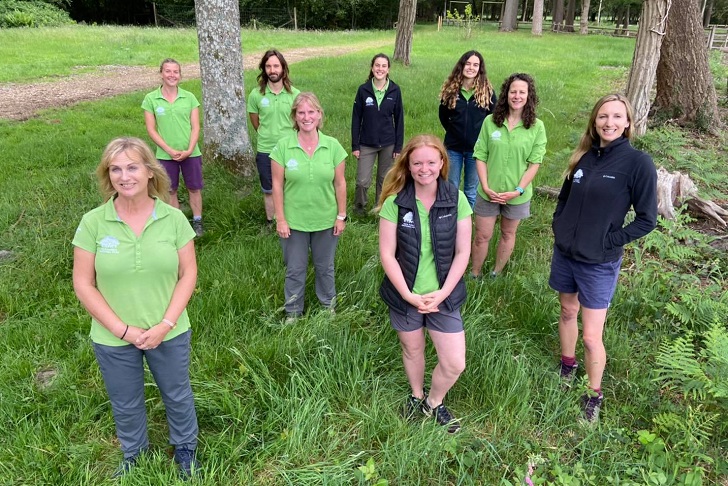 A group of women and a man in park ranger uniforms in countryside