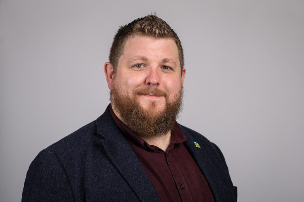 Head and shoulders of bearded man smiling