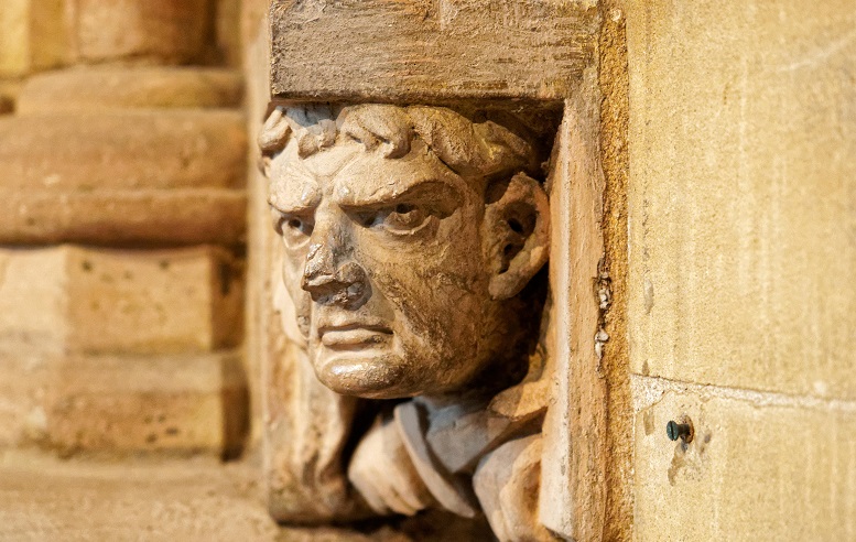 Carving of head of grumpy man in sand coloured stone
