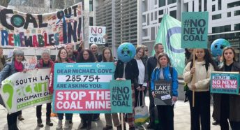 A row of people holding banners against coal power outside an office building