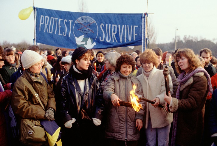 Greenham women with protect and survive banner lighting torches for evening march