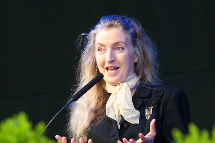Woman talking into microphone while gesturing with hands