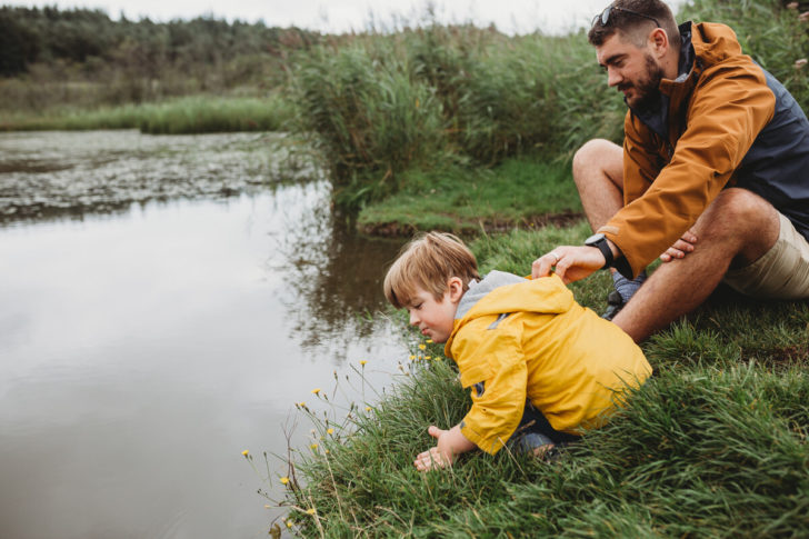 Father and young son peering into pond on grey day