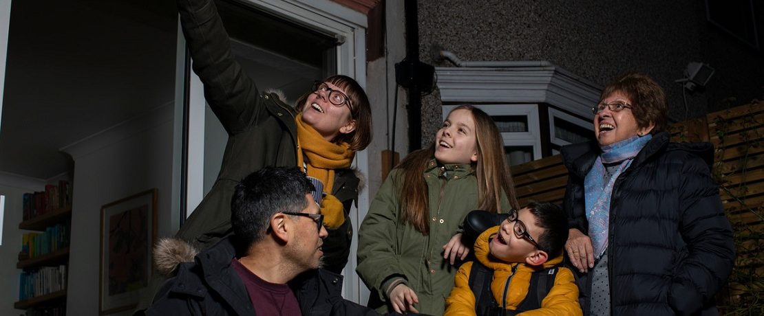 Family group in garden in dark pointing at stars.