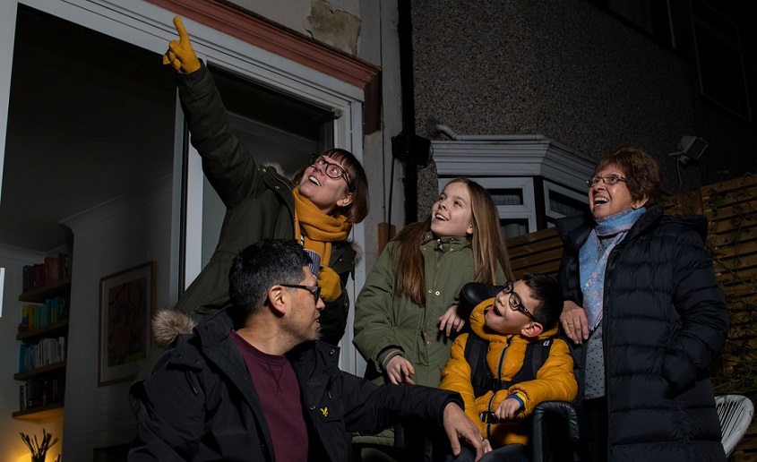 Family star gazing in garden.