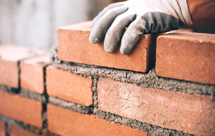 Close up of industrial bricklayer installing bricks on construction site.