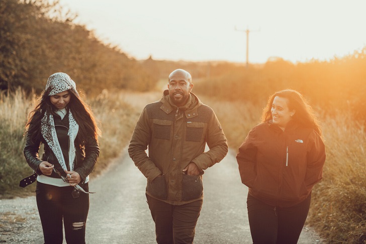 Three people walking along a country lane at sunset