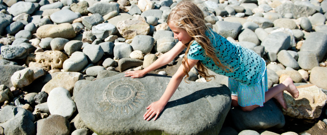 A girl looks at a giant fossil at the ammonite graveyard at Lyme Regis, Dorset.