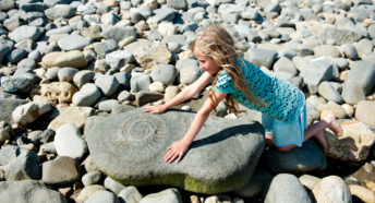 A girl looks at a giant fossil at the ammonite graveyard at Lyme Regis, Dorset.