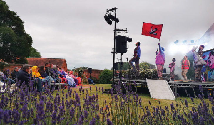 A youth theatre performs outside to a small audience, with lavender plants in foreground