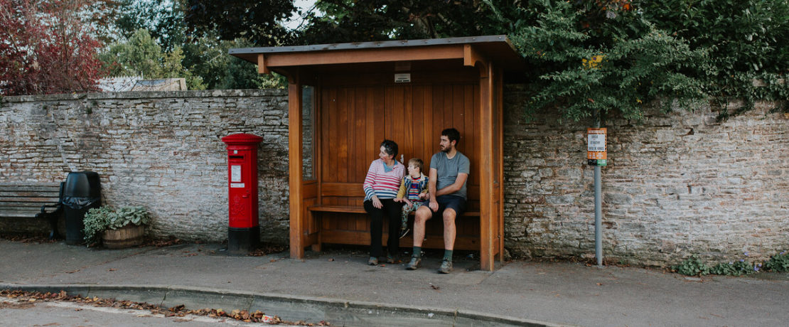 Family sat in a rural bus stop waiting for a local bus