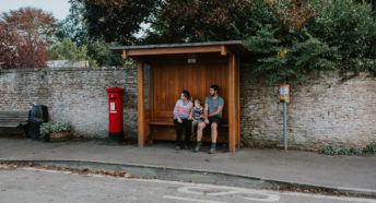 Family sat in a rural bus stop waiting for a local bus