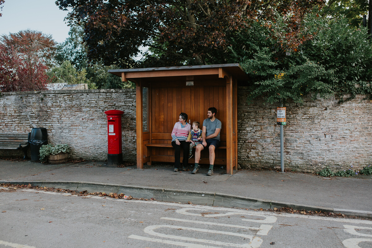 Family sat in a rural bus stop waiting for a local bus