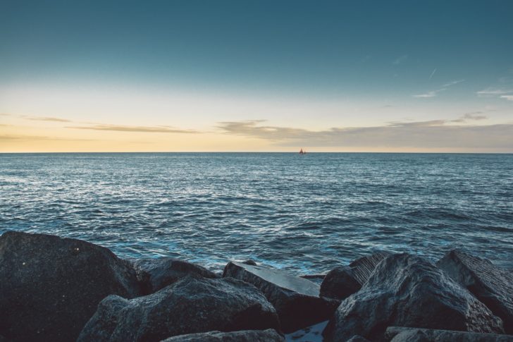 A sunset at Lyme Regis with large rocks in the foreground and a sea view