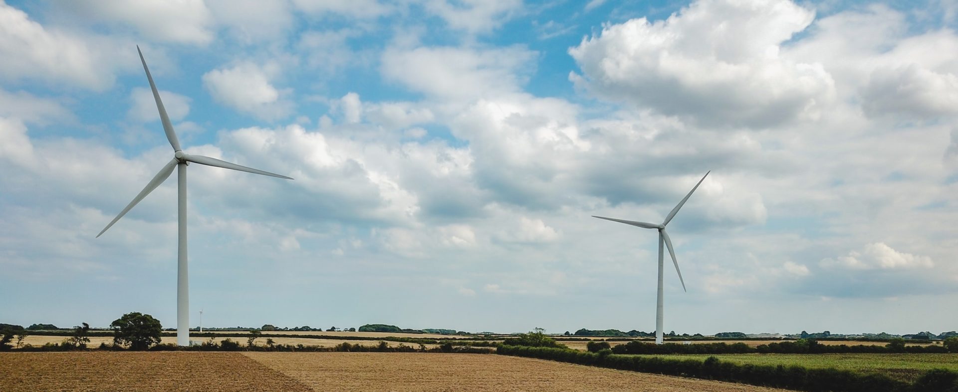 Farm being ploughed with wind turbines in background