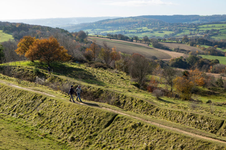 Man and women walking along a path with a big countryside view of farm fields and trees